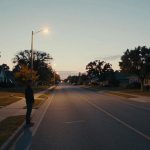 A man standing on a suburban street at dusk for a California wrongful death and hit-and-run compensation